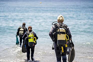 Three scuba divers with all equipment heading to the sea, Andalusia, Spain, Europe