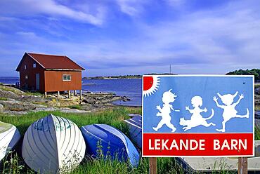 Children playing on traffic sign, boats in calm landscape, composition, Sweden, Europe