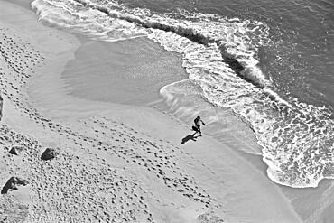 Man with guitar on lonely beach with footprints in sand, from above, Algave, Portugal, Europe