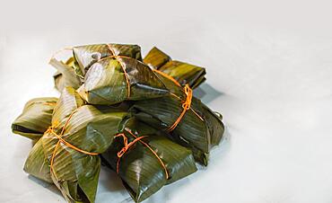 Close up of nacatamales with banana leaves on white background, tied nacatamales on white background