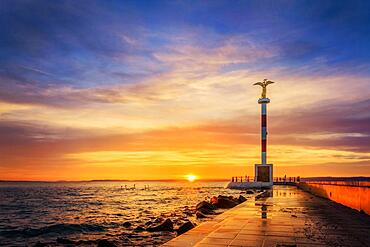 Shore at a lake, jetty of the harbour of Siofok. In the background there is a statue and the sun is setting, sunset in Siofik, Balaton, Lake Balaton, Hungary, Europe