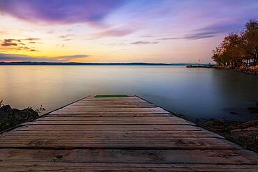 Shore at a lake, a jetty goes into the lake. In the background is a boat landing stage with sunset, long exposure Siofok, Balaton, Lake Balaton, Hungary, Europe