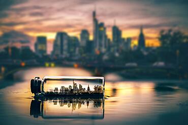 Frankfurt skyline in a small bottle, I reflected in a puddle, the skyscrapers in the banking district, sunset, Frankfurt am Main, Hesse, Germany, Europe