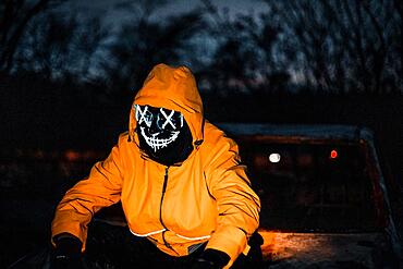 Man with Purge mask on a car wreck, at night, Frankfurt am Main, Hesse, Germany, Europe