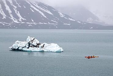 Canoeist in front of iceberg in St. Jonsfjorden, Spitsbergen Island, Norway, Europe