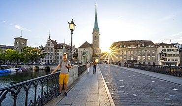 Tourist on the Muenster bridge over the river Limmat, Fraumuenster church, Zurich old town, sun star at sunset, Zurich, Canton Zurich, Switzerland, Europe