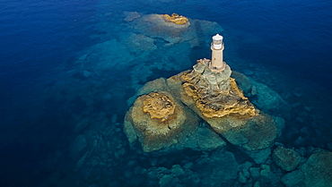 Drone shot, white round lighthouse on tiny rocky island, sea clear, sea blue and turquoise. Andros Town, Chora, Andros Island, Cyclades, Greece, Europe