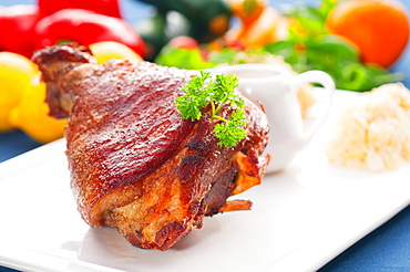 Original German BBQ pork knuckle served with mashed potatoes and sauerkraut, fresh vegetables on background