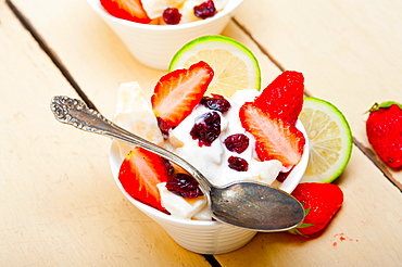 Fruit and yogurt salad healthy breakfast over white wood table