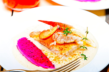 Sea bream orata fillet butter pan fried with fresh peach prune and dragonfruit slices thyme on top