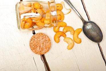 Cashew nuts on a glass jar over white rustic wood table