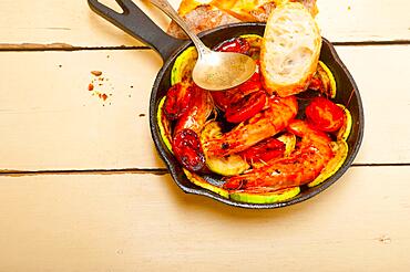 Roasted shrimps on cast iron skillet with zucchini and tomatoes