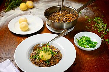 Goulash with chanterelles (Cantharellus cibarius) and a dumpling made of potato dough with a small salad and cooking pot