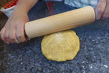 Southern German cuisine, baking, preparing the walnut dough for the hearty vegetable cake with walnut base, rolling out the dough, rolling pin, men's hands, Germany, Europe