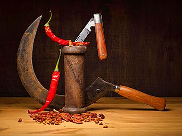 Food photography, still life with sickle, pocket knife, red peppers and chilli peppers, studio shot, symbol photo