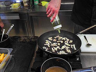 Chef cooking flambleing atlantic squid with olive oil in a big pan in a professional kitchen, trendy seafood recipe, Professional gourmet cooking concept