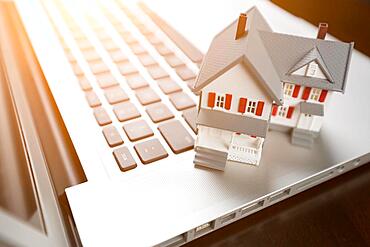 Miniature house and laptop computer resting on desktop