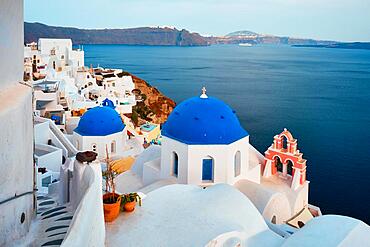 Famous view from viewpoint of Santorini Oia village with blue dome of whitewashed greek orthodox Christian church of traditional greek architecture. Oia town, Santorini island, Greece, Europe