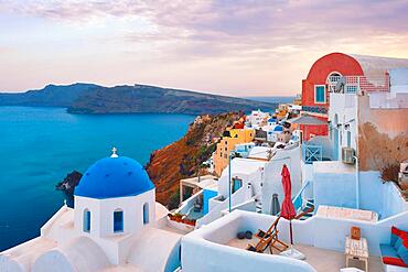 Famous view from viewpoint of Santorini Oia village with blue dome of whitewashed greek orthodox Christian church of traditional greek architecture. Oia town, Santorini island, Greece, Europe