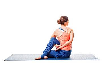 Beautiful sporty fit woman practices yoga asana Ardha matsyendrasana, half spinal twist pose isolated on white