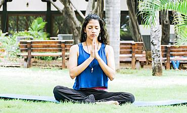 A girl sitting doing meditation yoga outdoors, Woman doing yoga outdoors, a young woman doing yoga with closed eyes