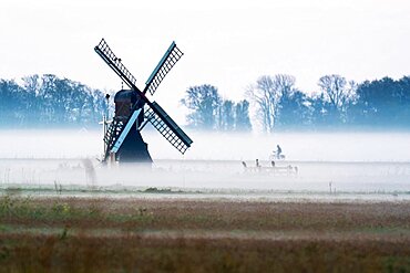 Morning atmosphere with windmill and cyclist, Texel, Netherlands