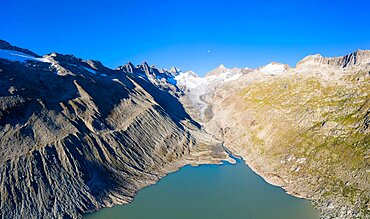 Aerial view over Lake Oberaar with the Oberaar glacier and the moon above the Bernese Alps, Canton Bern, Switzerland, Europe