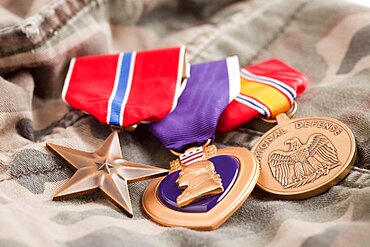 Bronze, purple heart and national defense medals on camouflage material