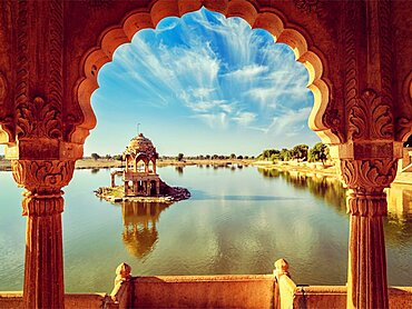 Vintage retro effect filtered hipster style image of Indian landmark Gadi Sagar, artificial lake view through arch. Jaisalmer, Rajasthan, India, Asia