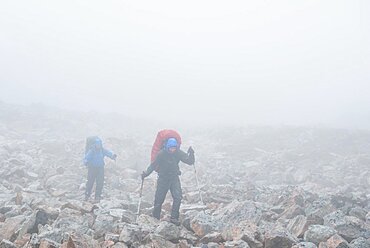 2 men with trekking equipment in rocky landscape, fog, rain, West Greenland, Greenland, North America