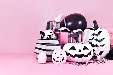 Pink Halloween decor with black and white pumpkins, spell books and spiders with copy space