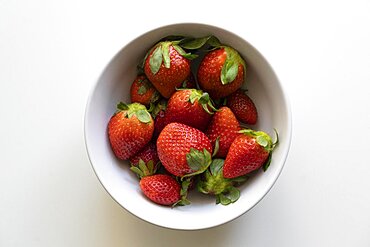 Top view of fresh strawberries in a white bowl isolated on white background