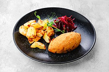 Kiev or pozharskaya cutlet served with fried potato and beet on a plate