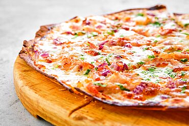 Thin-crust pizza dough with pulled beef, red onion and lot of melted cheese (closeup photo with shallow depth of field)