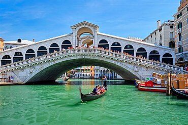 VENICE, ITALY, JULY 19, 2019: Rialto bridge with boats and gondolas passing under on Grand Canal, Venice, Italy, Europe