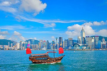 HONG KONG, CHINA, MAY 1, 2018: Hong Kong skyline cityscape downtown skyscrapers over Victoria Harbour with tourist junk boat on sunset. Hong Kong, China, Asia