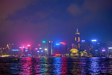 HONG KONG, CHINA, APRIL 28, 2018: Hong Kong skyline cityscape downtown skyscrapers over Victoria Harbour in the evening illuminated with tourist boat ferries, Hong Kong, China, Asia