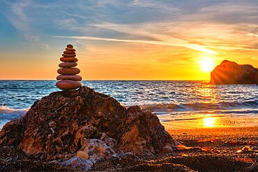 Concept of balance and harmony. Cairn stack of stones pebbles cairn on the beach coast of the sea in the nature on sunset. Meditative art of stone stacking