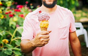 Unrecognizable people holding ice cream in cone outdoors. Front view of person hands holding an ice cream cone. People showing a double ice cream cone. Cone ball ice cream concept