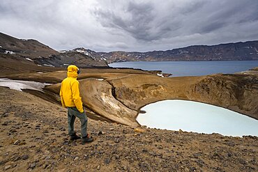 Tourist at the crater rim, crater lake Viti and Oeskjuvatn in the crater of Askja volcano, volcanic landscape, mountain massif Dyngjufjoell, Icelandic highlands, Vatnajoekull National Park, Iceland, Europe