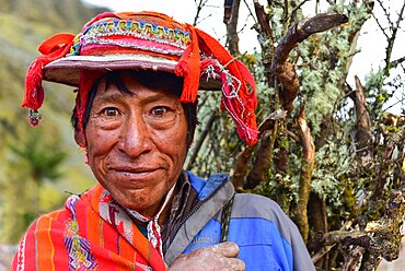 Man with colourful traditional hat and firewood on his back, Andes, near Cusco, Peru, South America