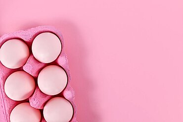 Easter eggs in box on pink background with copy space