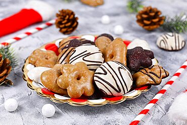 German gingerbread cookies with sugar and brown and white chocolate glazing in heart and star shape called Lebkuchen on striped plate surrounded by seasonal Christmas decoration