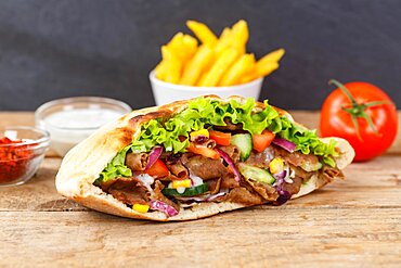 Doener Kebab Doner Kebap fast food meal in pita bread menu with fries on wooden board in Stuttgart, Germany, Europe