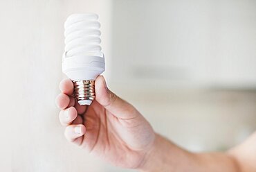 Human hand holding compact fluorescent light bulb