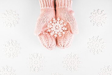 Human hands mittens with paper snowflake