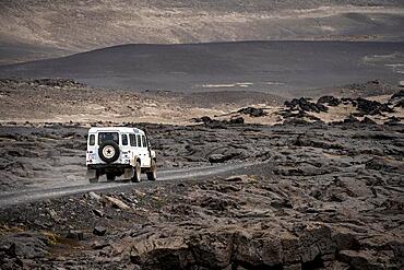 White Land Rover on a dirt road, volcanic landscape, barren landscape, Vatnajoekull National Park, Icelandic Highlands, Iceland, Europe