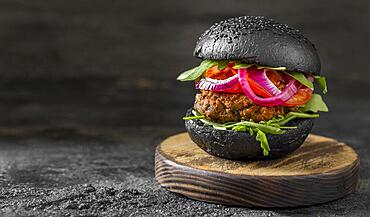 front view veggie burger with black buns cutting board