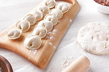 Handmade homemade dumplings on a wooden tray on a white plate with flour. Diy meat dumplings