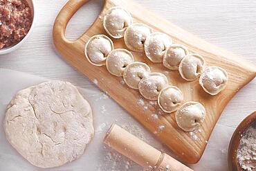 Handmade homemade dumplings on a wooden tray on a white plate with flour. Diy meat dumplings